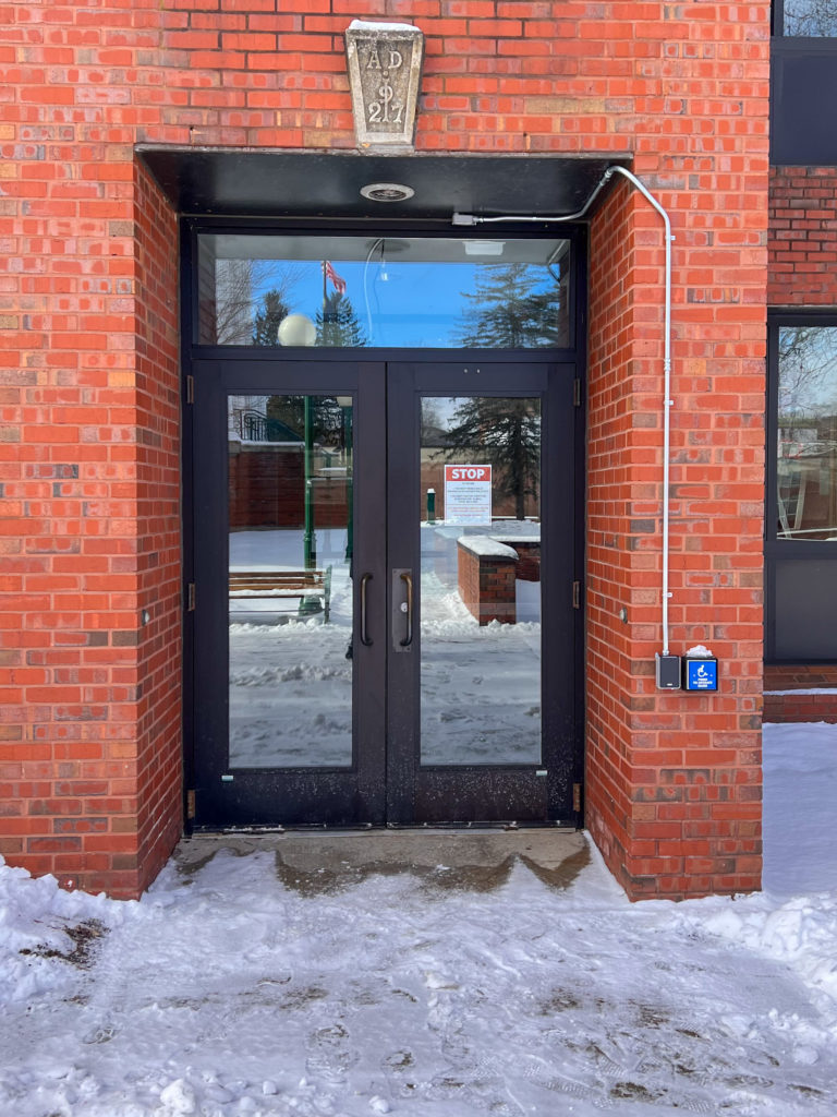 A photo of an accessible door with a button for a wheelchair user to press to open.